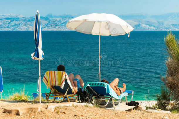 希腊科孚岛海滩上的日光浴床和雨伞（阳伞）