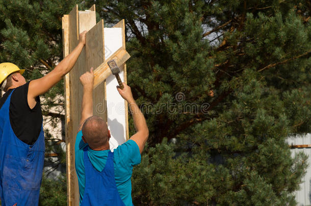 两个建筑工人在新房子上安装墙板