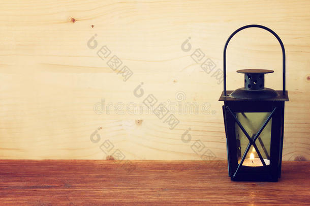 木制桌子上有燃烧蜡烛的老式灯笼。过滤后的图像。