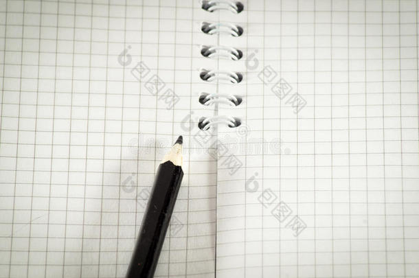 在公开的记事本背景上的黑色铅笔。