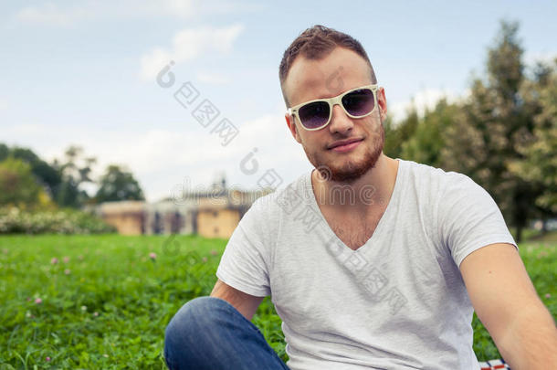 有胡子的年轻人的画像。在阳光明媚的夏天或春天，在公园外微笑的白人男子