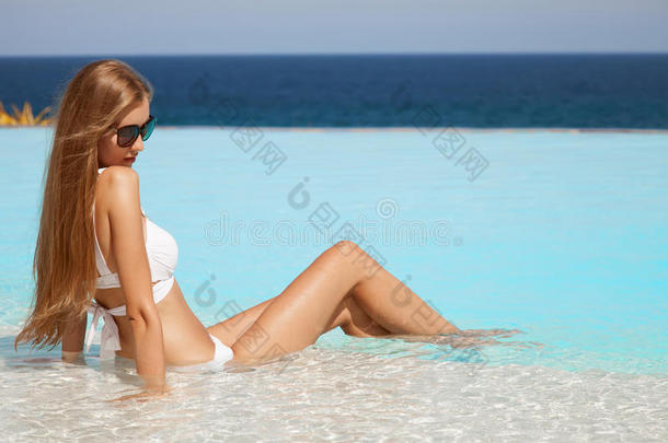 年轻漂亮的<strong>女人</strong>在游泳池里<strong>晒太阳</strong>。海景不错