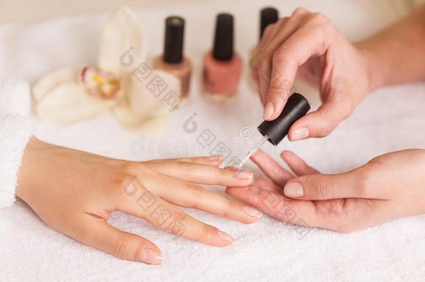 美女美甲师在美容院为女人修指甲。