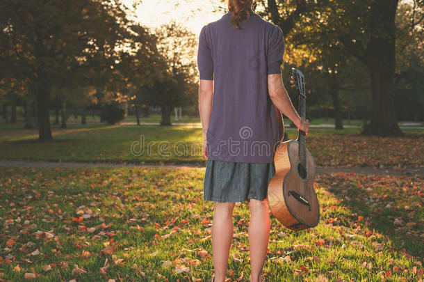 日落时分公园里拿着吉他的女人