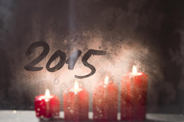 2015年新年，在磨砂的窗户上点燃圣诞蜡烛