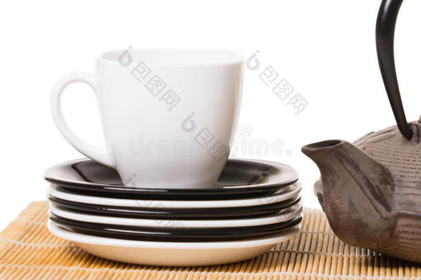 白茶杯放在不同的碟子上，铁制茶壶放在木头上
