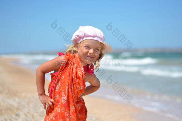 一个穿着橘色连衣裙在海滩上摆姿势的年轻女孩