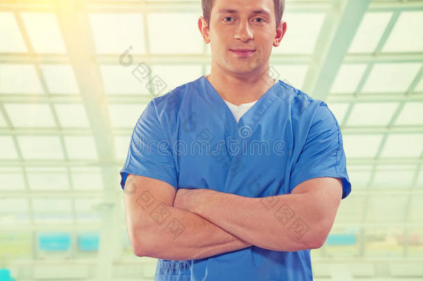英俊的年轻医生交叉着双臂看着大窗口instagram stile背景下的摄像机