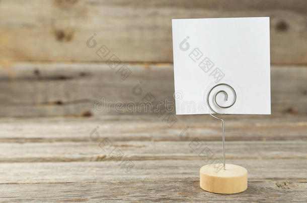 灰色木质背景上的白色便笺夹。