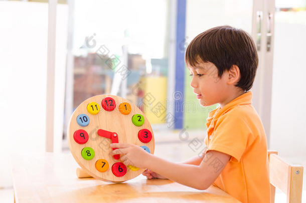 蒙台梭利教材中的小男孩用钟表玩具学习时间