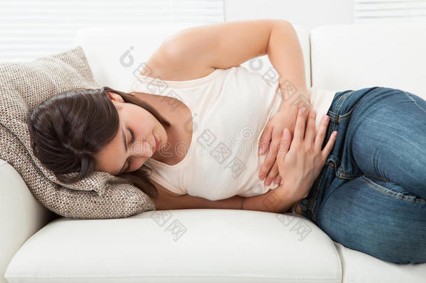 坐在沙发上胃痛的女人