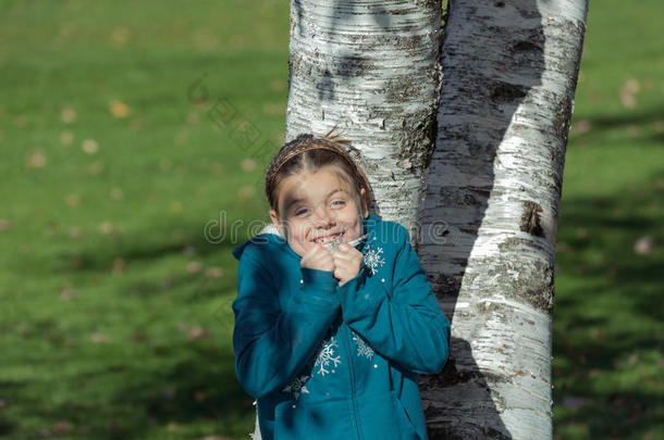 阳光明媚的秋天公园里，躲在白桦树后面，阳光普照，快乐快乐的女孩