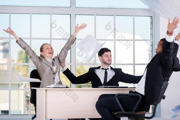 你好。 三位成功的商人扔掉文件，而商人则享受着他们在办公室里的成功。