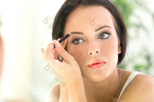 年轻漂亮的女人用眼睑涂抹<strong>眼线笔</strong>