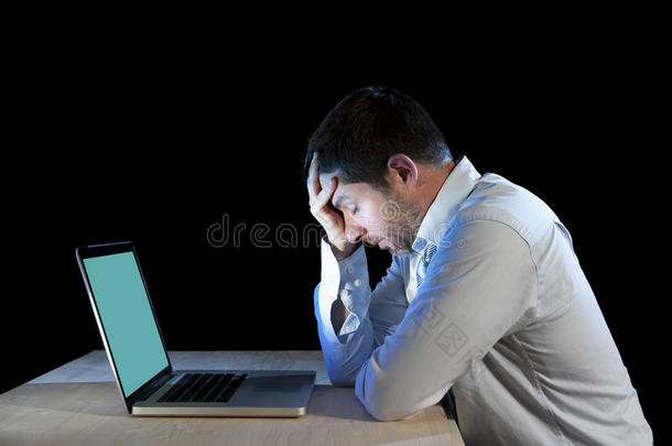 年轻的压力很大的商人在沮丧和沮丧中拿着笔记本电脑在办公桌上工作