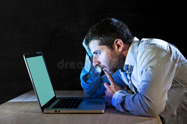 年轻的压力很大的商人深夜在桌上用笔记本电脑工作