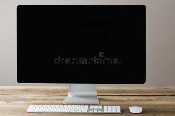 电脑屏幕和键盘鼠标放在一张木制的桌子上