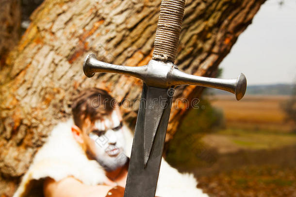 一位肌肉发达的古代战士的画像。前景中的剑