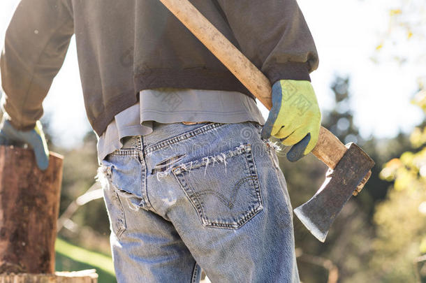 一个穿着脏牛仔裤的男人在砍柴