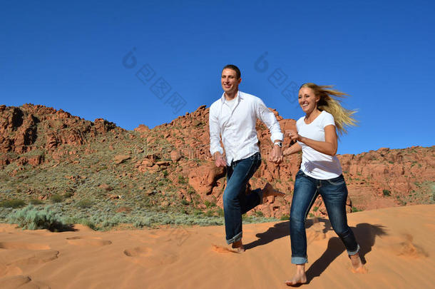 相爱的年轻情侣在沙丘上奔跑
