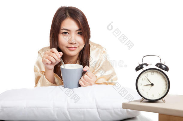 快乐的亚洲女孩带着闹钟和咖啡杯醒来