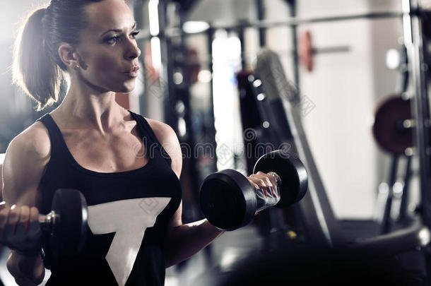 运动型迷人的女人在健身房里用健身器材