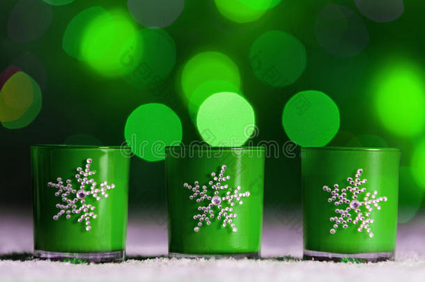 蜡烛站在雪中，有散焦的仙女灯，背景是绿色的波基，节日的圣诞节背景