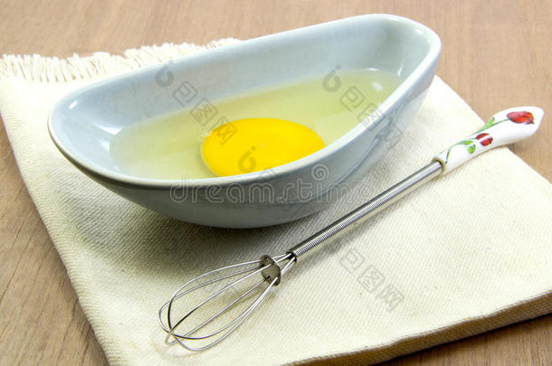木桌上的生鸡蛋和打蛋器