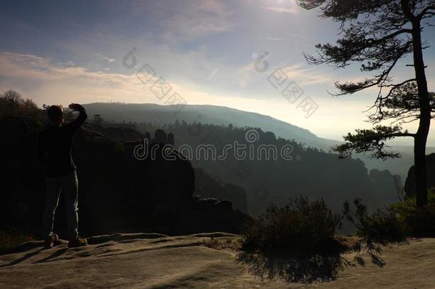 人们站在岩石帝国公园的砂岩山顶上，看着薄雾蒙蒙的晨间山谷向阳。