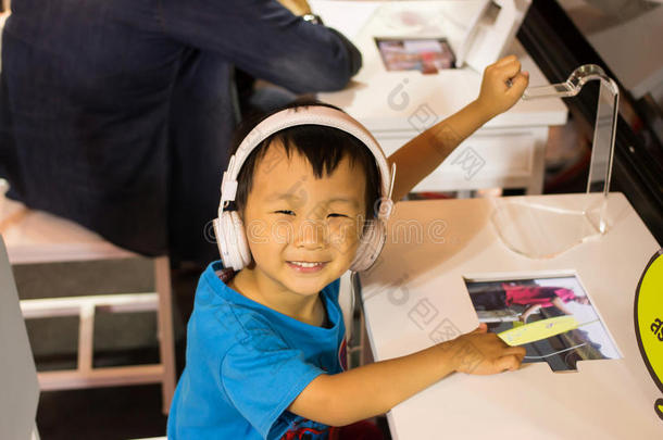 亚洲小孩玩电脑游戏，戴耳机