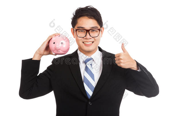亚洲商人竖起大拇指拿着一只粉红色的小猪存钱罐