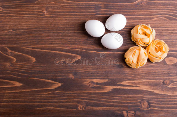 生意大利面，三个圆和三个白鸡蛋，放在一个棕色的木制t形桌上