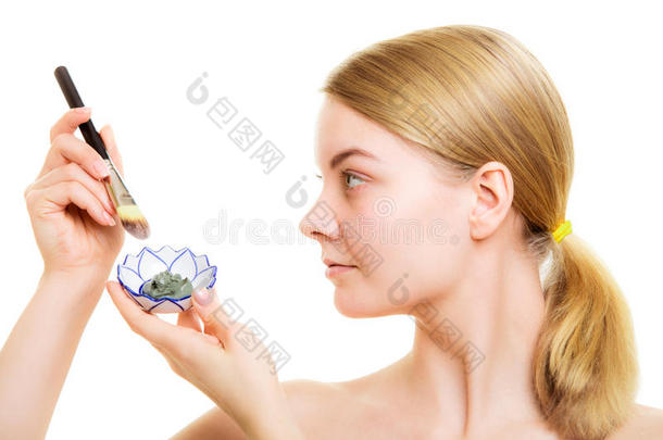 皮肤护理。女人在脸上涂泥巴面膜。