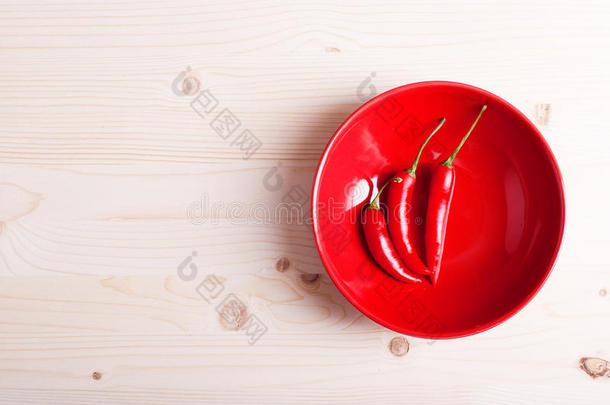红辣椒放在盘子里，放在一个浅木的桌面上
