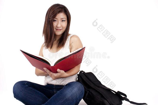 美丽的亚洲年轻女子背着书包读红皮书