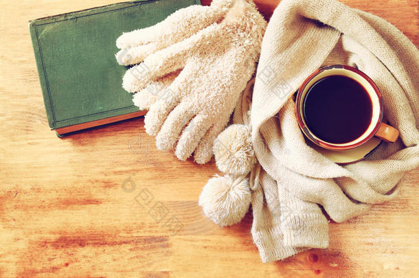 一杯黑咖啡，一条温暖的围巾和一本旧书放在木质背景上。被窃取的图像。