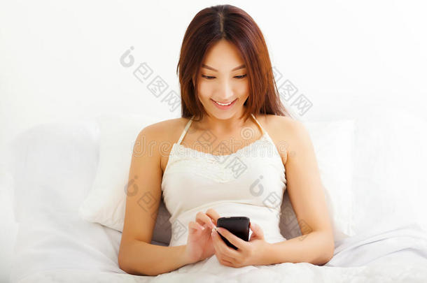 躺在床上用智能手机躺在床上的年轻女子