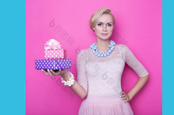 穿着米色连衣裙的漂亮年轻女子拿着粉色和紫色的礼盒