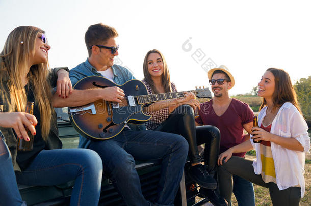 一群玩吉他和喝啤酒的朋友的画像。