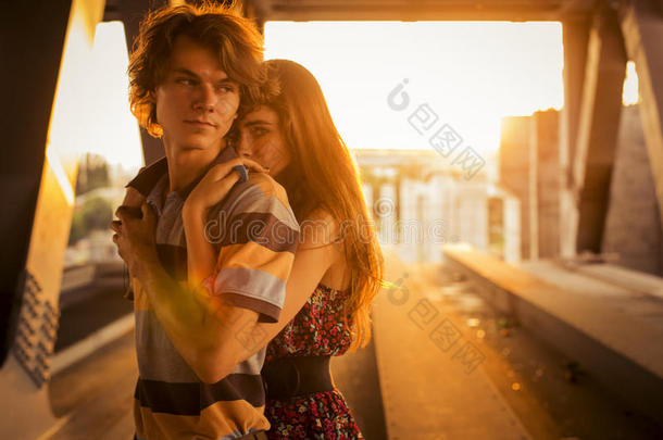 一对年轻夫妇在c桥上的夕阳余晖中拥抱