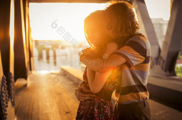 一对年轻夫妇在c桥上的<strong>夕阳余晖</strong>中拥抱