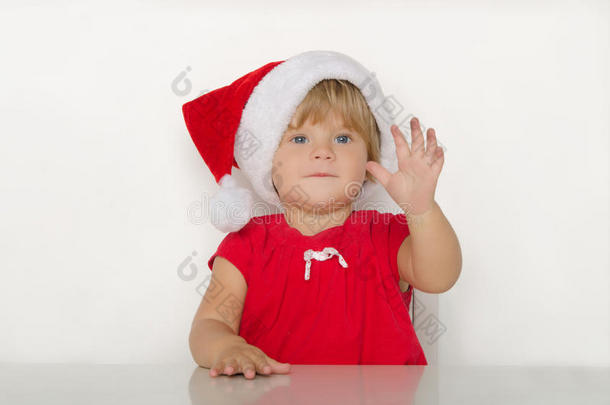 快乐的小女孩穿着圣诞老人的服装在餐桌上