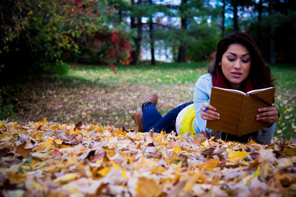 足协秋叶上躺着看书的年轻女子