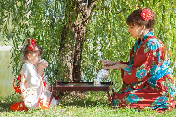 小女孩和穿着和服的妈妈坐在茶几旁