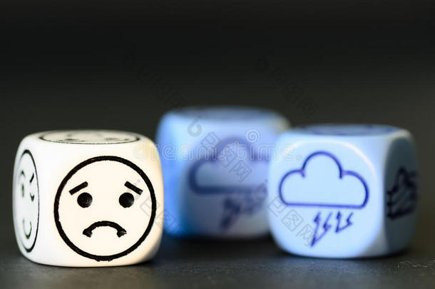 悲伤风暴天气的概念-黑色背景上的表情符号和天气骰子