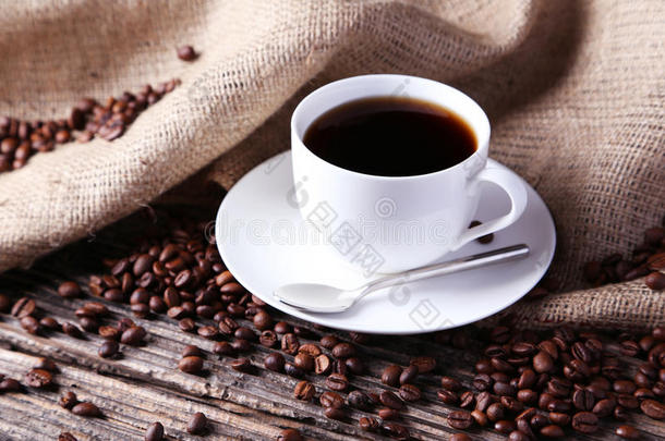 一杯咖啡，咖啡豆<strong>放在</strong>棕色<strong>木质</strong>背景上。