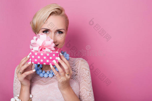 生日快乐。可爱的金发女人拿着一个带缎带的小礼盒。柔和的颜色