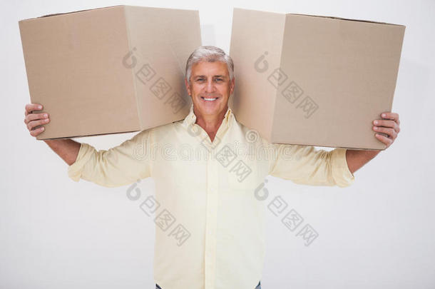 微笑的男人平衡着沉重的纸板箱