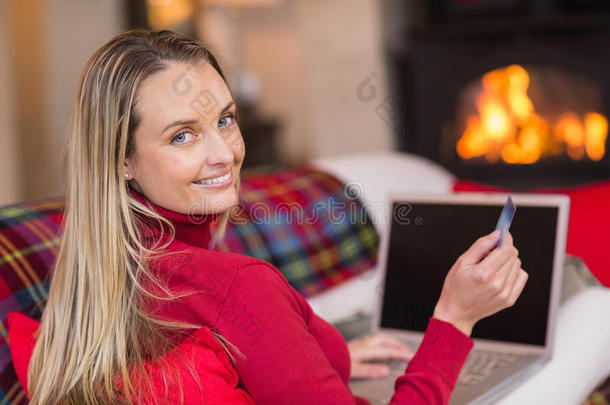 圣诞节时微笑的金发女郎用笔记本电脑上网购物