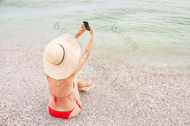 度假的女人正在用智能手机做自画像。